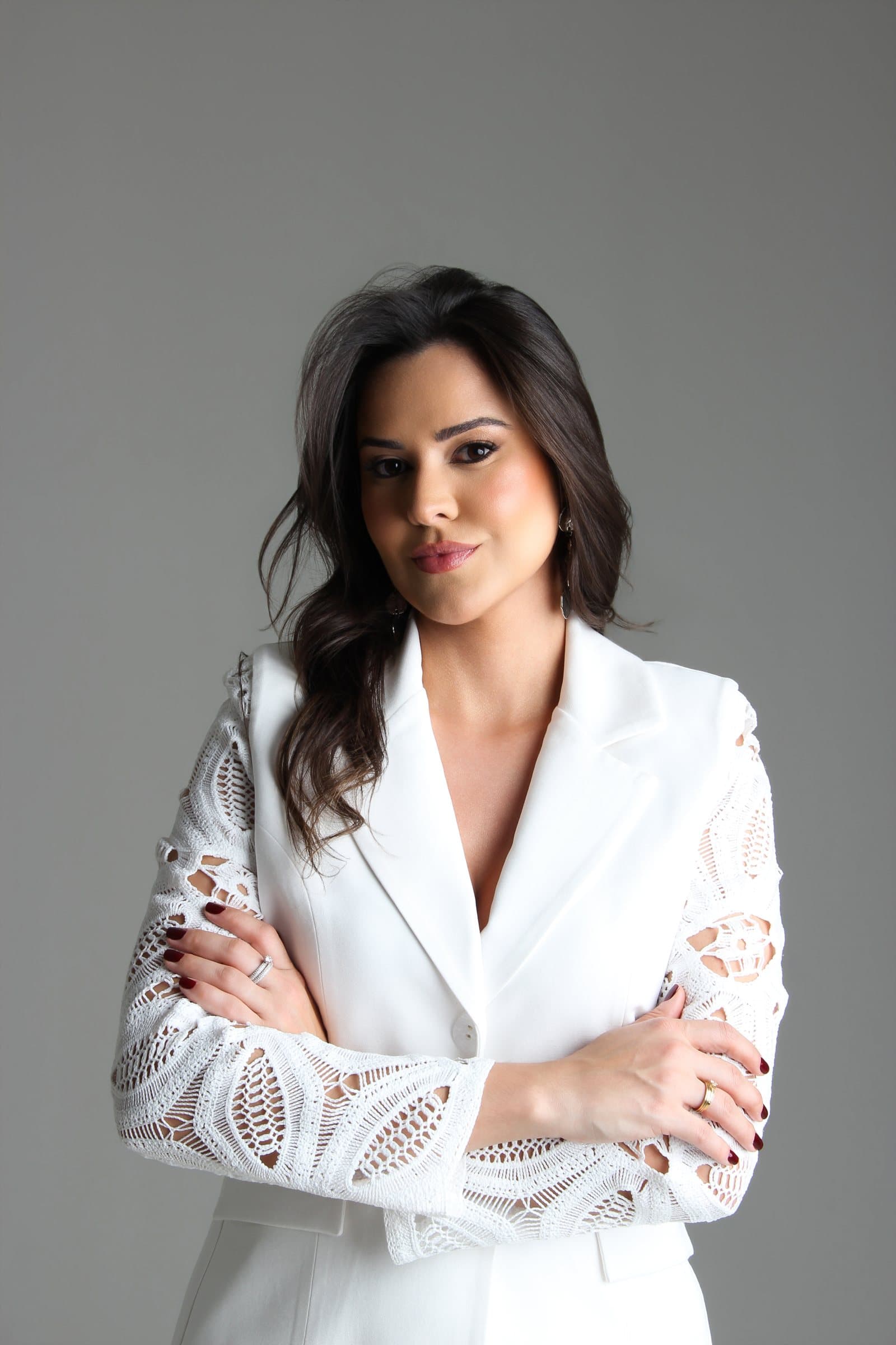 Dra. Bruna Couto de braços cruzados, vestindo blazer branco